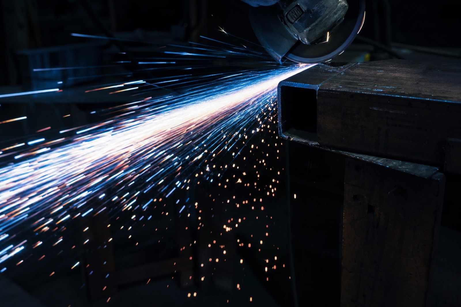 Angle grinding sparks cascading from a steel beam
